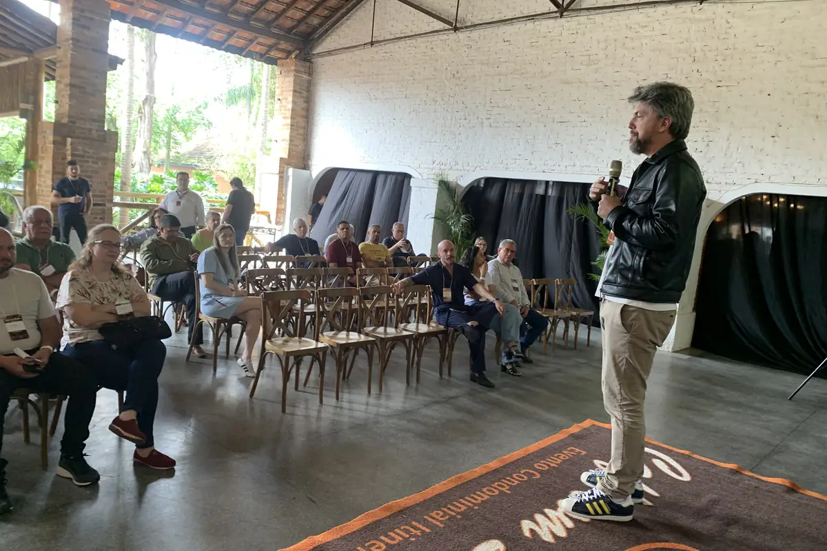 William Borghetti no Café com Síndico, em Piracicaba, em pé diante da plateia, escutando a pergunta de um participante
